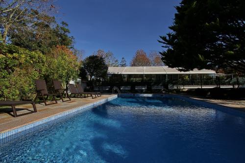 a swimming pool with benches and a building in the background at Villa das Rosas in Sintra