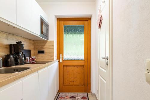 a kitchen with white cabinets and a wooden door at Auszeit am Fluss - Donau in Obernzell