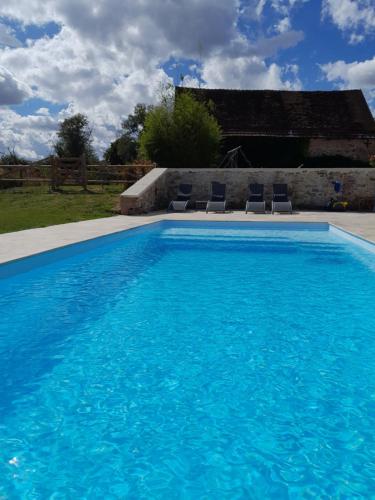 une piscine avec deux chaises et une maison dans l'établissement Gîte au centre de la France, à Vesdun