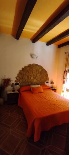 a bedroom with a large bed with an orange bedspread at Casa Rural La Higuera in El Gastor