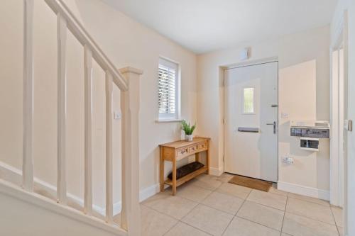 a hallway with a staircase with a table and a door at Cosy 3 bedroom spacious House in Romford