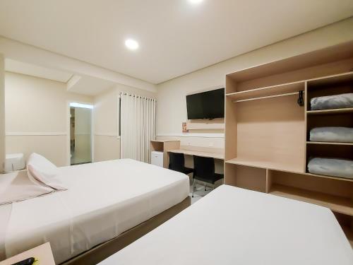 a hotel room with two beds and a desk at Hotel Itamarati Centro-República in Sao Paulo