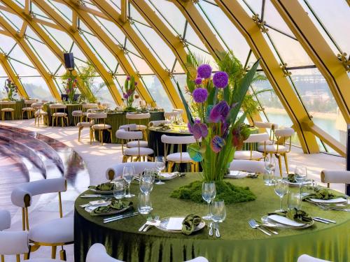 a dining tent with tables and chairs and purple flowers at voco Dubai Monaco, the Heart of Europe by IHG in Dubai