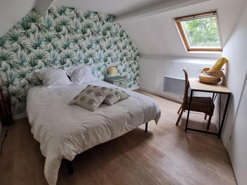 a bedroom with a bed and a table with a window at Les Brassins du Dillon in Moyon