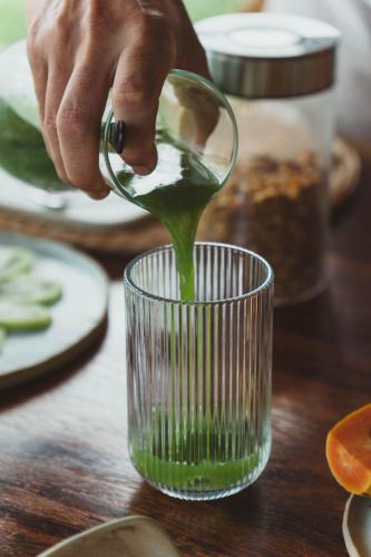 a person pouring green liquid into a glass on a table at 4 Coqueiros GURIU in Guriú