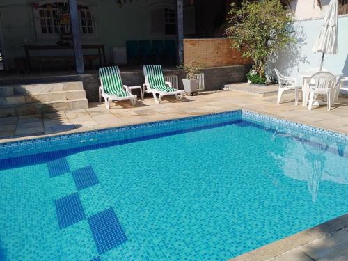 una piscina con dos sillas y una mesa en Cabo Frio, a melhor temporada, com menor preço., en Cabo Frío