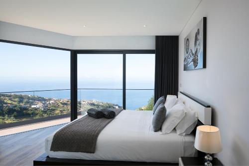 a bedroom with a large bed with a large window at Villa Panorâmica III in Arco da Calheta