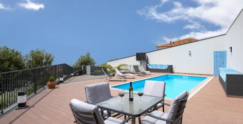 a patio with a table and chairs next to a swimming pool at Villa Panorâmica III in Arco da Calheta