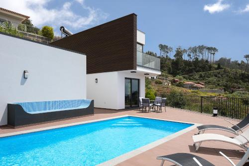 a villa with a swimming pool and a house at Villa Panorâmica III in Arco da Calheta