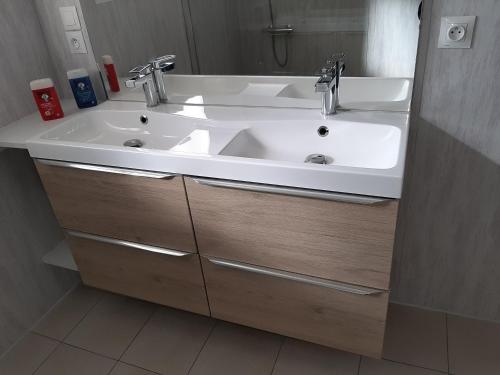 La salle de bains est pourvue d'un lavabo blanc et de placards en bois. dans l'établissement gite petit ecotay, à Saint-Symphorien