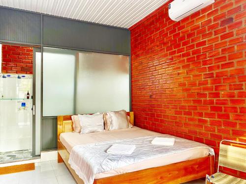 a bedroom with a brick wall and a bed at Cat Tien Backpackers Hostel in Cat Tien