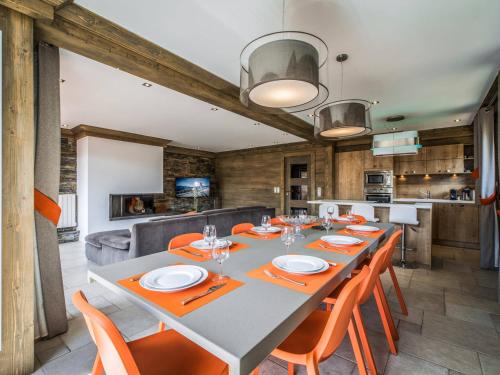 une salle à manger avec une grande table et des chaises orange dans l'établissement Appartement de charme skis aux pieds à Courchevel 1650 - FR-1-575-133, à Courchevel