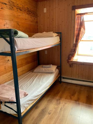 two bunk beds in a cabin with a window at Auberge jeunesse de Tadoussac in Tadoussac