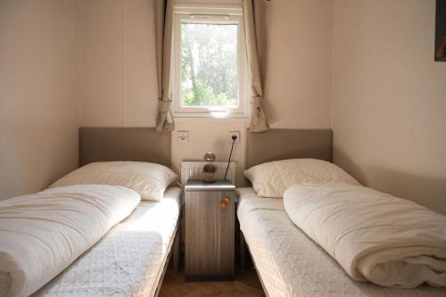 zwei Einzelbetten in einem Zimmer mit Fenster in der Unterkunft Forest Finest, luxe chalet met HOT TUB mooie overkapping en prachtige tuin met veel privacy in Hoenderloo