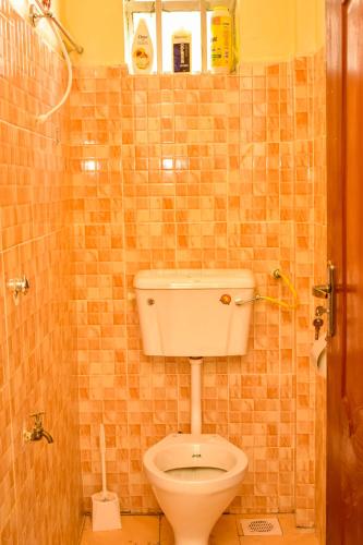 a bathroom with a toilet in a tiled wall at Spacious studio Apt Milimani in Kisumu