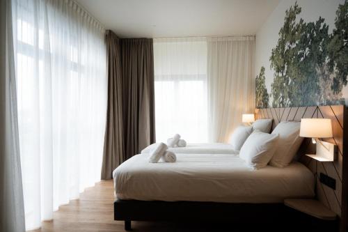 a bedroom with a large white bed with white pillows at Bô Hôtels Ambronay in Ambronay