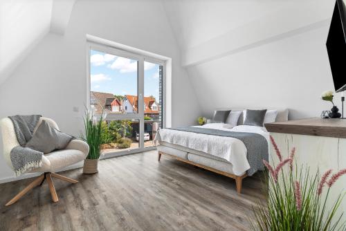 a bedroom with a bed and a chair and a window at Ferienhaus Donnerkeil Fehmarn in Fehmarn