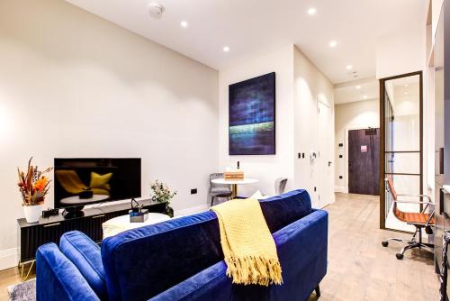 a living room with a blue couch and a tv at Luxury Apartments near Canary Wharf in London