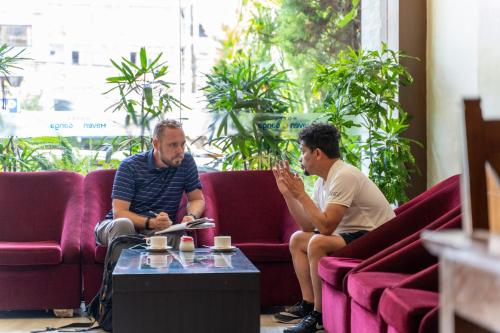 two men sitting on purple couches in a room at Hotel Haven O' Ganga in Pokhara