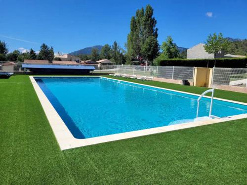a swimming pool in a yard with green grass at Les roses 49 in Castellane
