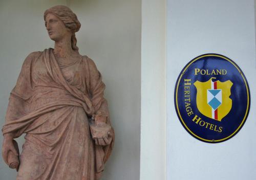 a statue of a woman next to a wall with a sign at Dwór Prezydencki Boutique Hotel & SPA in Tarnów