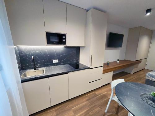 a kitchen with white cabinets and a sink and a table at Studio Apartman Petrinja in Petrinja