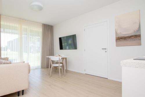 a white living room with a table and a chair at SMĖLĖTOS KOPOS - Mano jūra 3 in Kunigiškiai