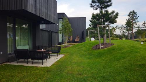 a yard with chairs and a table in the grass at SMĖLĖTOS KOPOS - Mano jūra 3 in Kunigiškiai