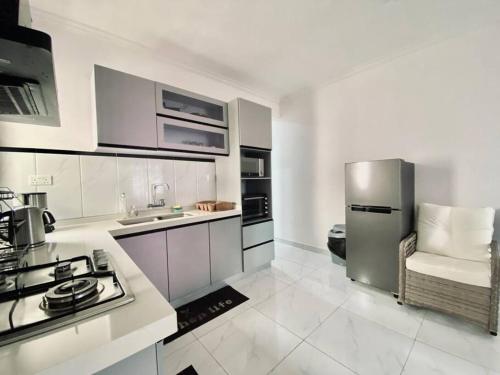 a kitchen with white cabinets and a stainless steel refrigerator at 3-Bedroom Apt with Oceanviews, 1min Walk to Beach - NYHA2 in Flic-en-Flac