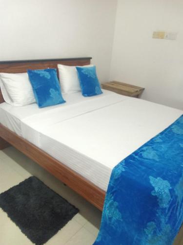 a bed with blue pillows in a room at Ceylon Beach haven Uppuveli in Trincomalee
