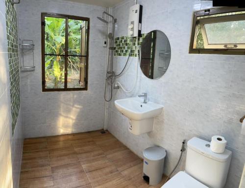 a bathroom with a sink and a toilet and a mirror at Croc Camp in Lat Krabang