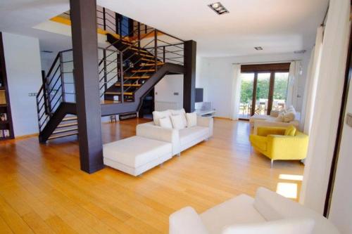 una sala de estar con muebles blancos y una escalera de caracol en La Casa de Orviz, en Siero