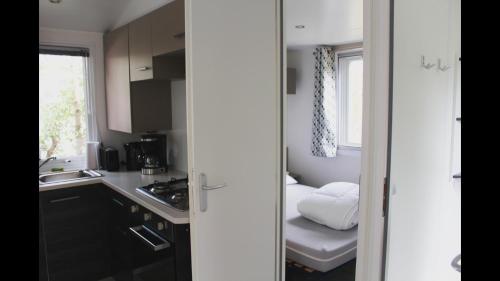 une petite cuisine avec un évier et un lit dans l'établissement Bungalow Camping 4 à 8 personnes, aux Mathes