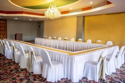 a row of chairs in a room with white tables and chairs at Hotel Plaza San Martin in Tegucigalpa