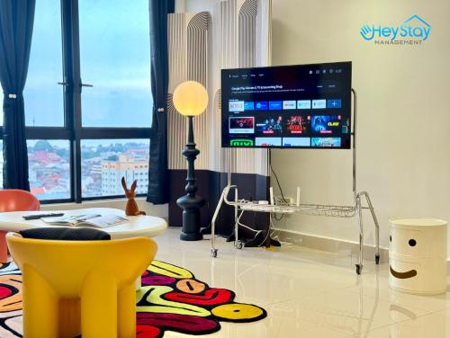 a living room with a tv and a yellow chair at The Apple Residence By Heystay Management in Melaka