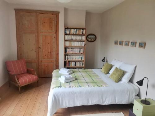 a bedroom with a bed and a chair and a book shelf at La Canolière - Chambre d'hôtes Camille in Sauveterre-Saint-Denis