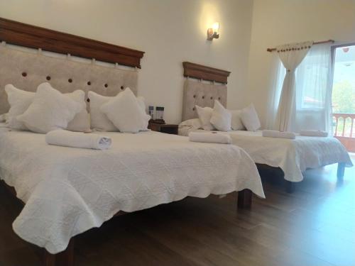 a bedroom with two beds with white pillows at Hotel las Palmas in Villa de Leyva