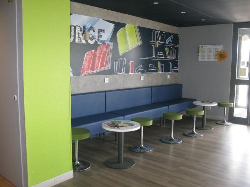 a waiting room with green stools and a blue bench at ibis budget Clermont Ferrand Nord Riom in Riom