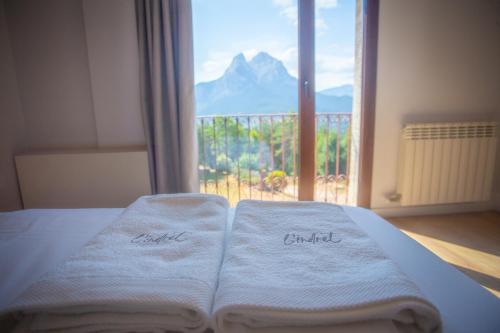 two towels on a bed in front of a window at L'indret del Pedraforca Adults Only in Saldés