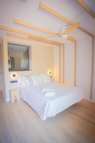 a bedroom with a large white bed with a ceiling fan at L'indret del Pedraforca Adults Only in Saldés