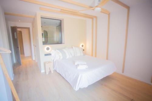 a white bedroom with a white bed and a mirror at L'indret del Pedraforca Adults Only in Saldés