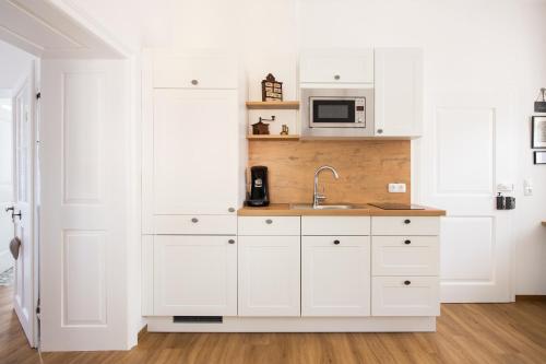 a white kitchen with a sink and a microwave at Leopold an der Ybbs in Waidhofen an der Ybbs