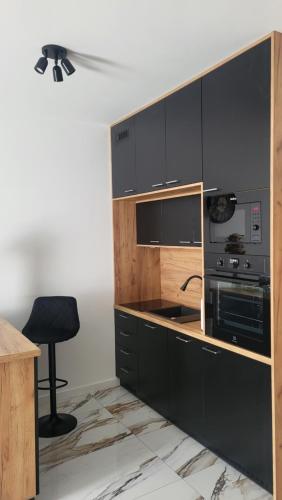 a kitchen with black cabinets and a black stool at Apart Paderewskiego in Bartoszyce