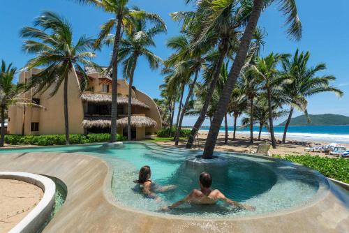 two people in a pool at a resort with palm trees at Mar de Coco Areca 102 in Barra de Potosi