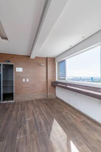 an empty room with a large window and wooden floors at PALMAS EXPERIENCE - APARTAMENTO BRISA, no centro, vista lago! in Palmas