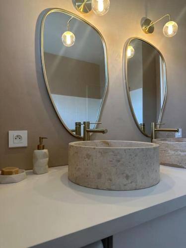 La salle de bains est pourvue d'un lavabo en marbre et de 2 miroirs. dans l'établissement Appartement - 90m 2 - Blois, à Blois