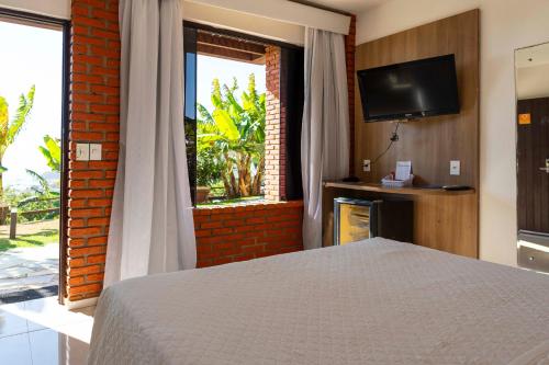 a bedroom with a bed and a tv and a window at Costa do Sol Boutique Hotel in Búzios