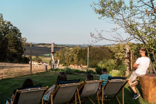a man walking past a group of people sitting in chairs at Wellness hiša Jelenov Grič in Mala Nedelja