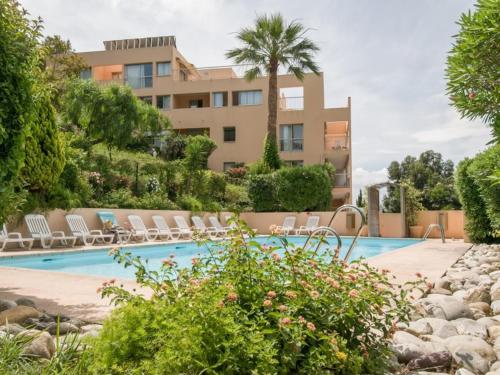 une piscine avec des chaises longues et un bâtiment dans l'établissement F3 à Cannes Résidence Villa Livia Pierre et Vacances, à Cannes