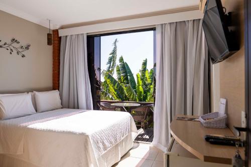 a bedroom with a bed and a window with a balcony at Costa do Sol Boutique Hotel in Búzios